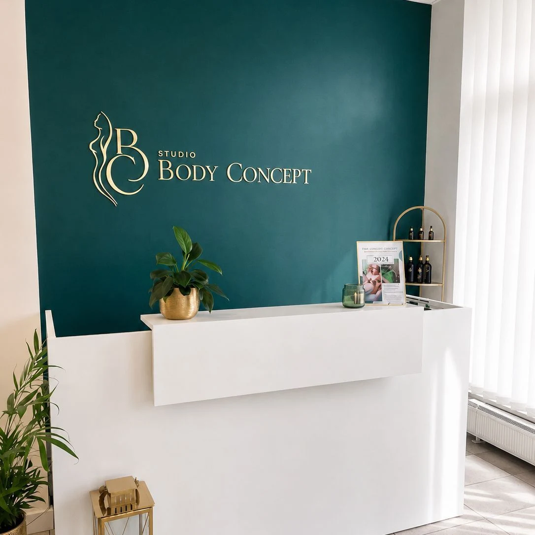 Recepcja Studio Body Concept — zielona ściana ze złotym logo